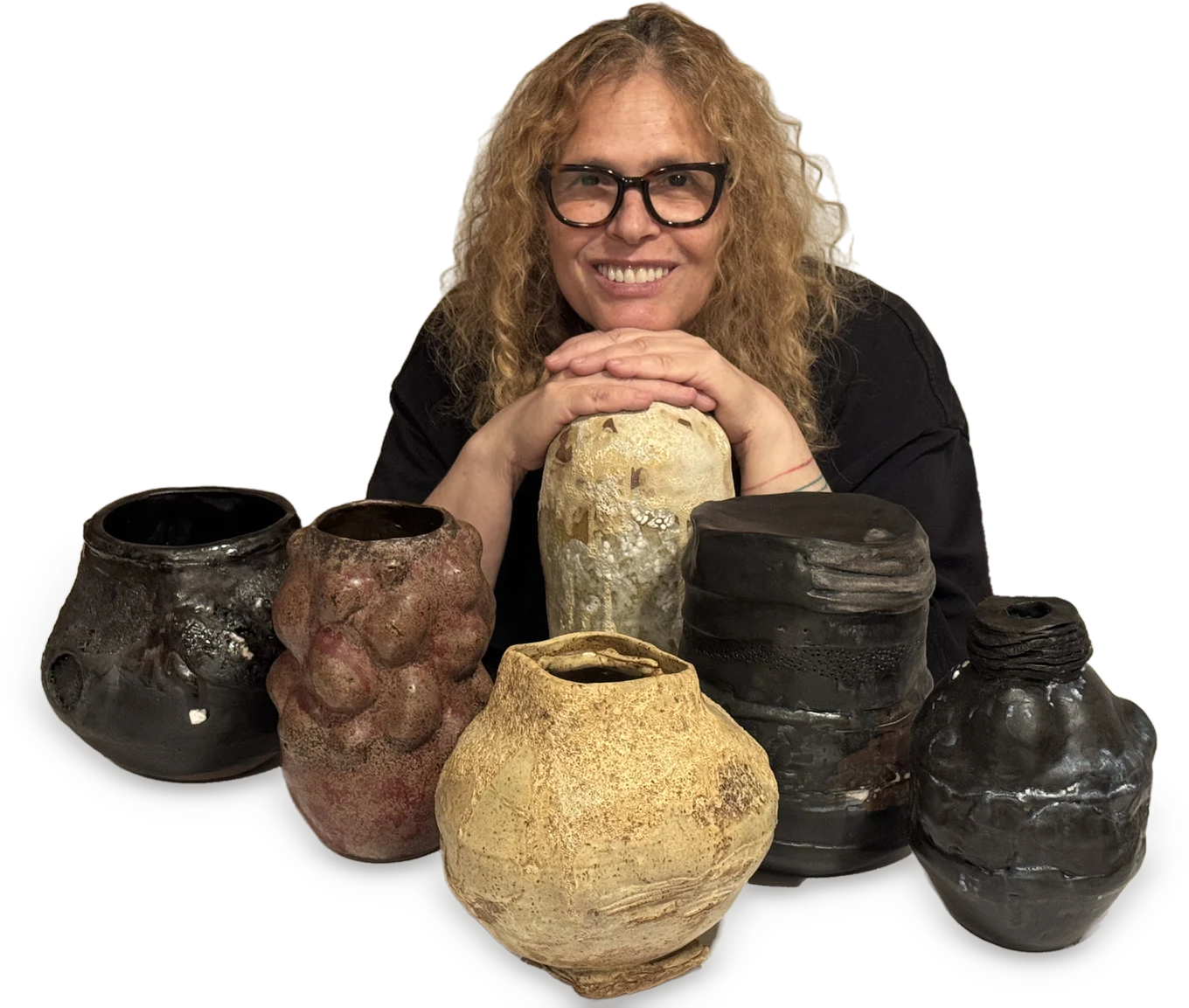 Yael Aloni-Netzer smiling behind a group of her hand-built ceramic vessels